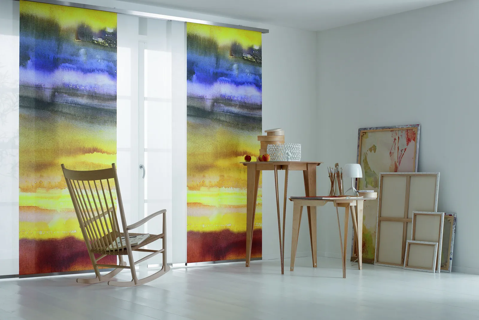 Flächenvorhänge mit farbigem Aquarellmuster neben einem Schaukelstuhl