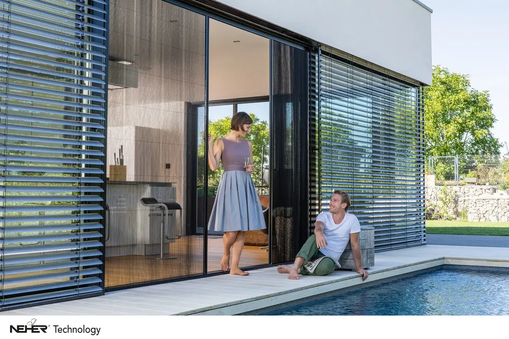 Großflächiger Insektenschutz an einer raumhohen Glasfront am Pool, davor zwei Personen