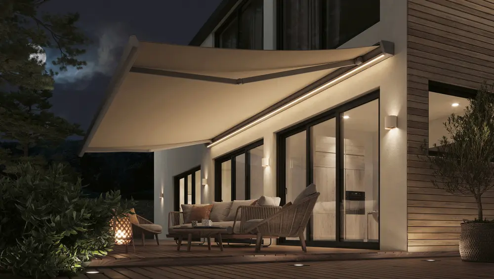 Gelenkarmmarkise am Abend mit eingebauter LED-Leiste, die die Terrasse beleuchtet