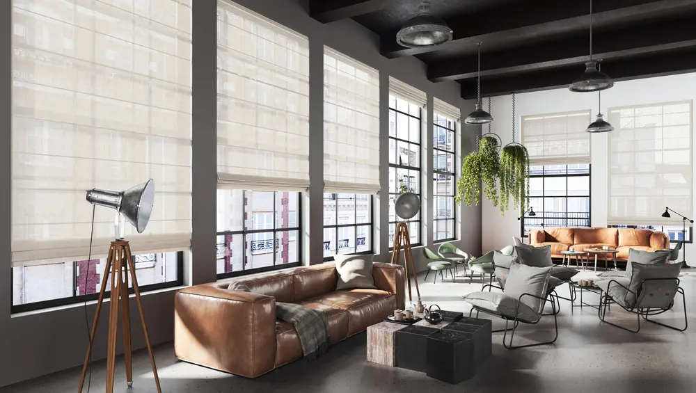 Loft mit hohen Sprossenfenstern, beigen Raffrollos aus Leinenstoff und braunem Ledersofa